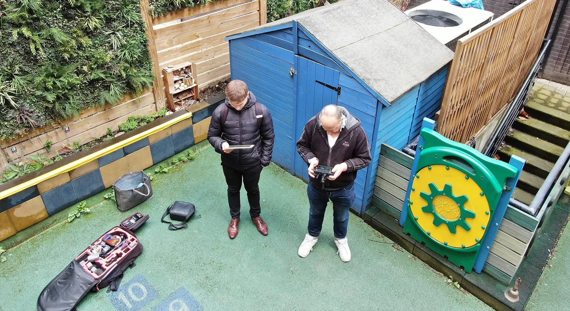 Aerial view of a professional drone survey team operating flight controls and monitoring equipment for a property inspection.