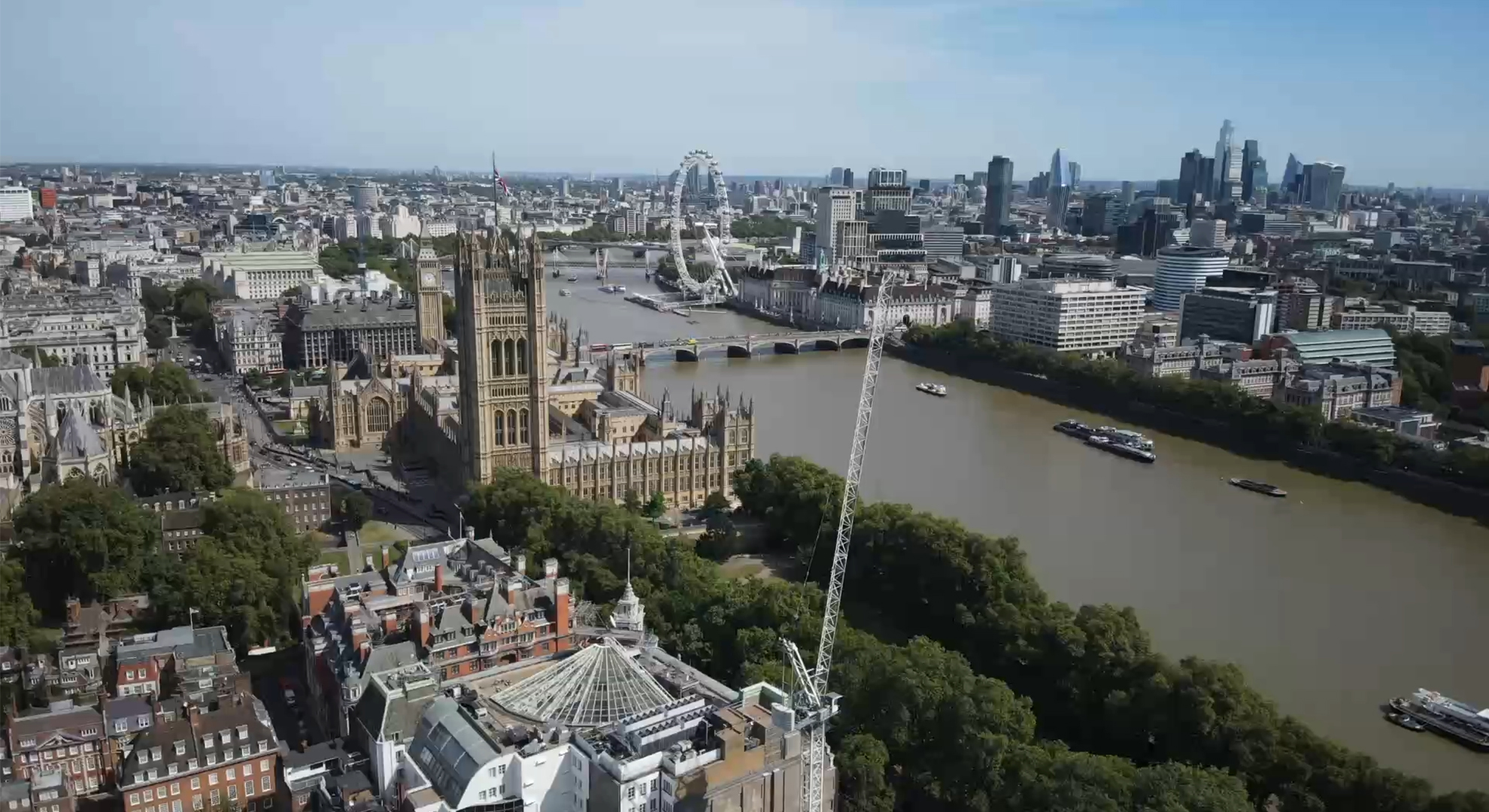 Aerial view of London via drone, featuring the Palace of Westminster, River Thames, and London Eye