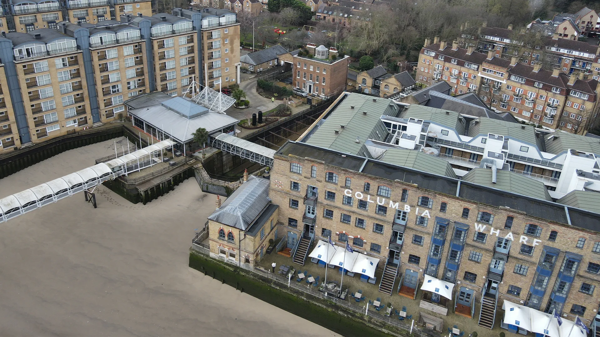 Aerial drone view of the Columbia Wharf brick building complex and walkway along the waterfront.